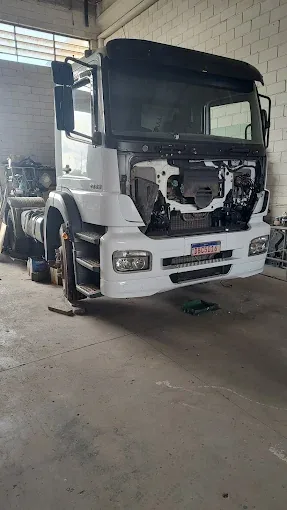 Caminhão branco com componentes dianteiros removidos para manutenção