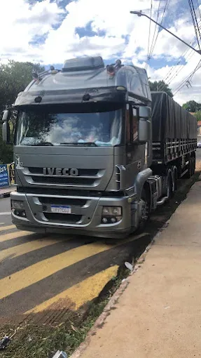 Caminhão Iveco cinza com carreta visto pela dianteira